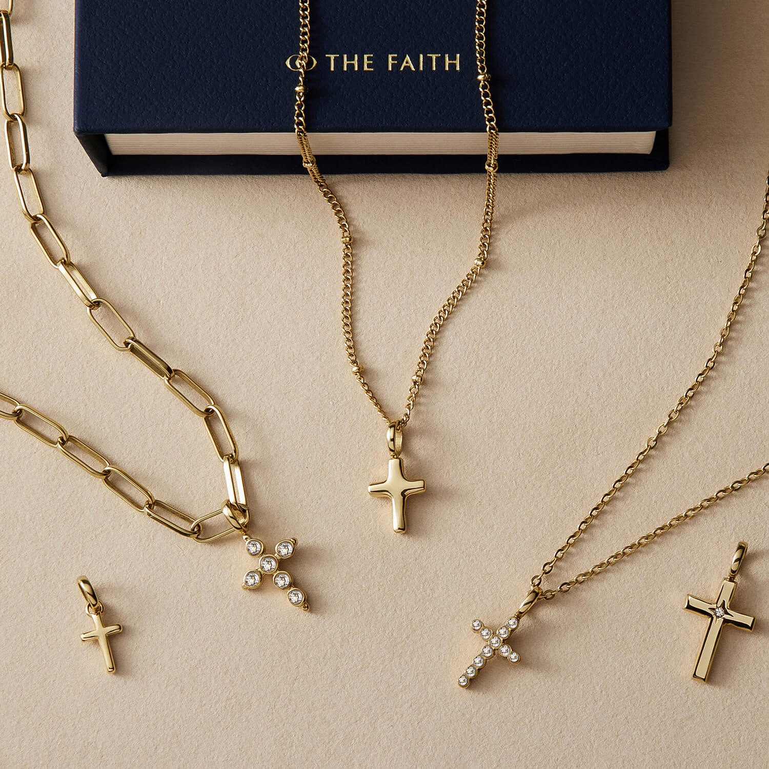 A styled flat-lay image of gold cross pendants and necklaces.