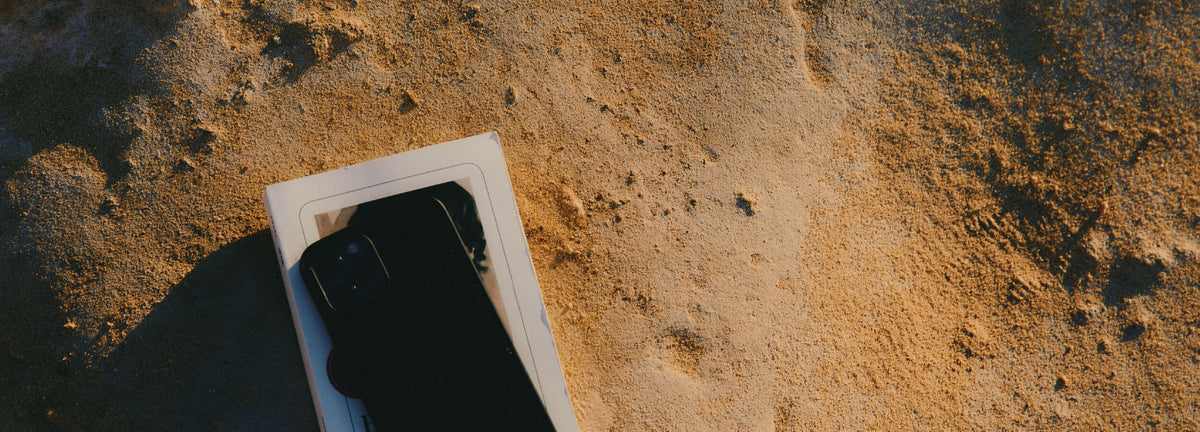 Black smartphone with a white case on a textured brown surface.