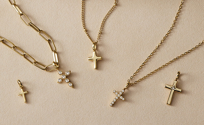 A styled flat-lay image of gold cross pendants and necklaces.